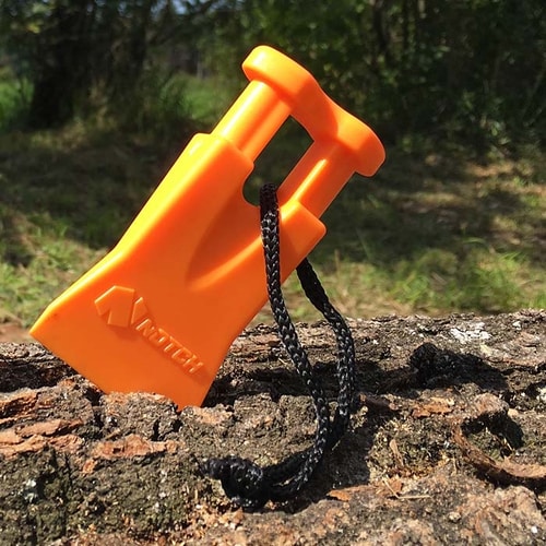 Climbers Best Friend Wedge par Notch, cale en plastique orange avec cordon noir repose en diagonale sur l’écorce d’un arbre à l’extérieur