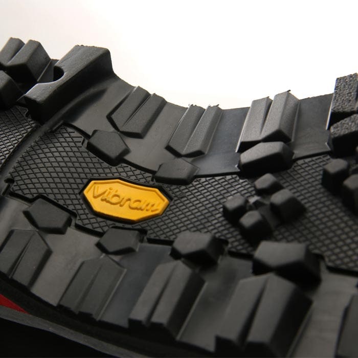 Gros plan sur la semelle crantée noire avec logo Vibram jaune