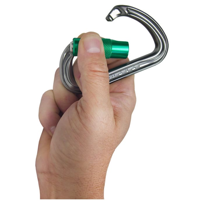 Mousqueton Shadow avec capuchon à vis vert, fabricant DMM, type non visible tenu d’une main sur fond blanc