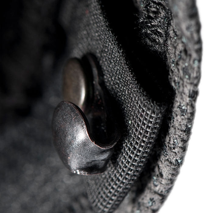Gros plan d’un bouton en métal noir sur un tissu, faisant probablement partie du pantalon Arborist Progress