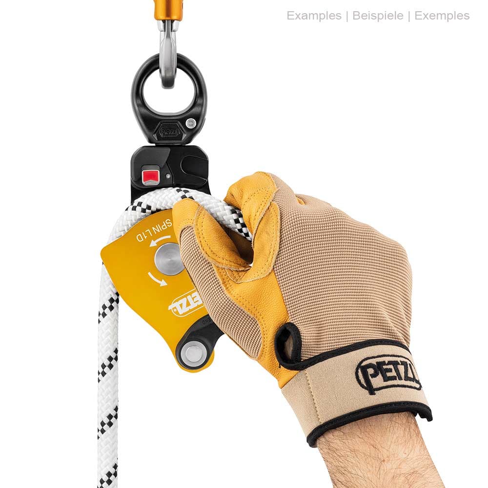 Poulie Petzl Spin L1D avec gant sur une main tenant une corde blanche