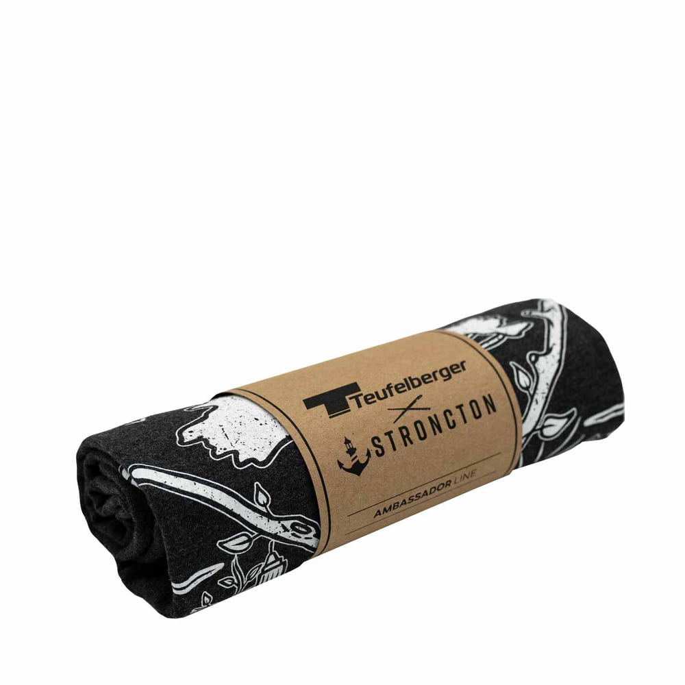 T-shirt tSPIRIT en gris foncé, plié et emballé avec un ruban de papier brun avec les logos de Teufelberger et Stroncton
