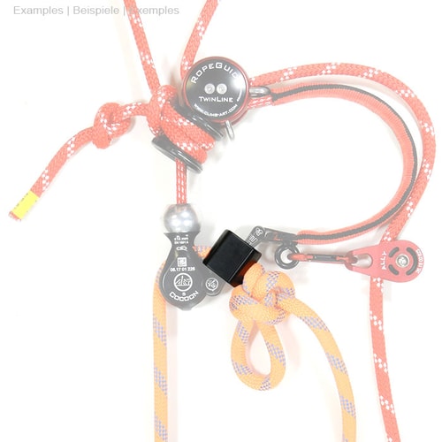StopperGate pièce en plastique noir sur cordes rouges et oranges avec nœuds et pièces métalliques, fond blanc