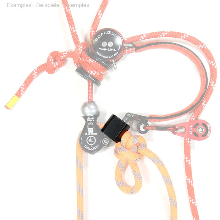 StopperGate pièce en plastique noir sur cordes rouges et oranges avec nœuds et pièces métalliques, fond blanc