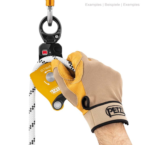 Poulie Petzl Spin L1D avec gant sur une main tenant une corde blanche