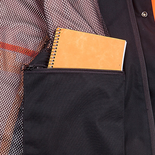 Intérieur de la veste de pluie Keiu avec poche zippée noire contenant un carnet orange