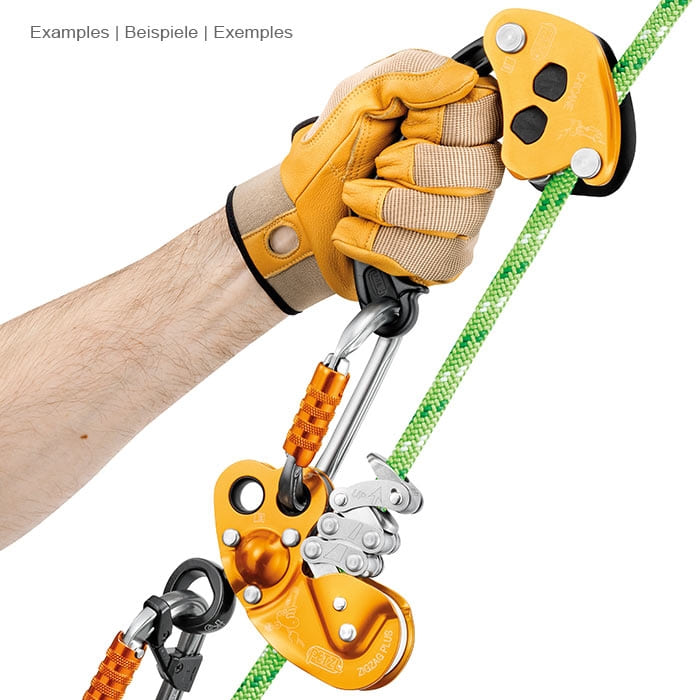 Chicane Petzl, appareil d’assurage jaune et noir avec poignée, tenu par une main avec un gant jaune, relié à un mousqueton et un appareil d’assurage jaune sur une corde verte