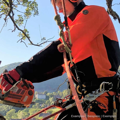 Personne portant la veste Herma de Francital en orange et noir lorsqu’elle travaille avec du matériel d’escalade et une tronçonneuse